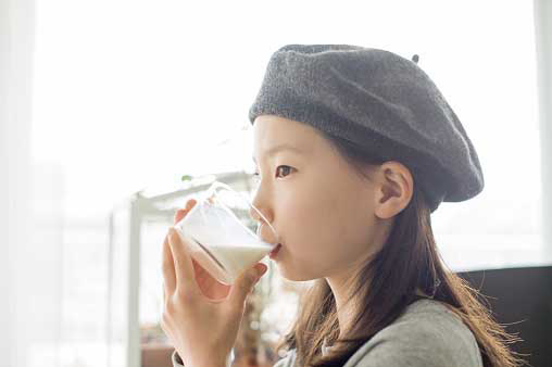 young girl drinking milk from glass